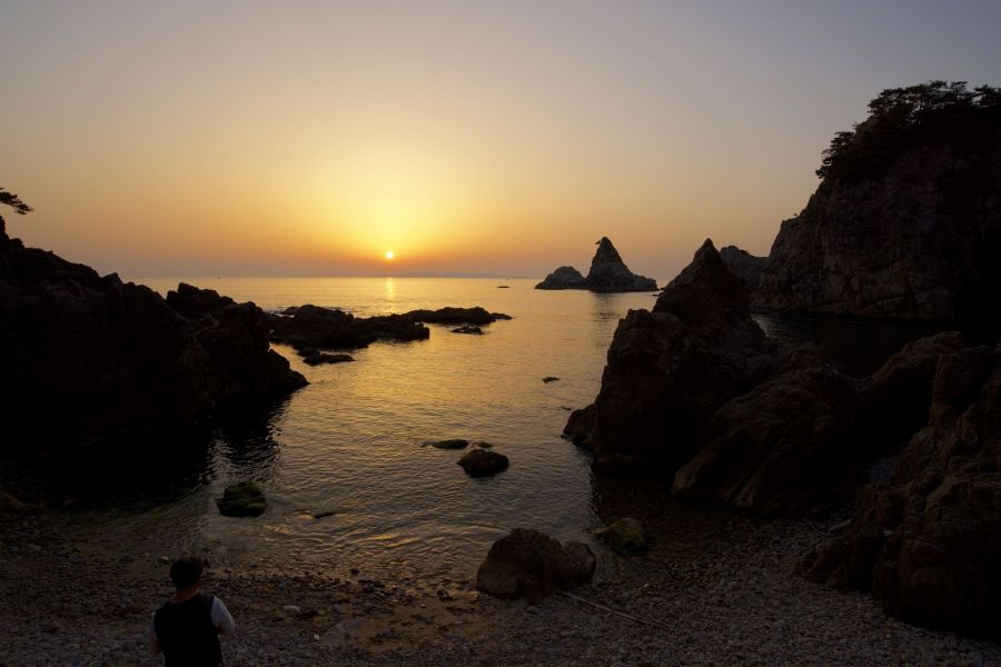 日本海の水平線に沈む夕日を眺める