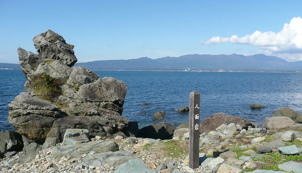 真野湾を背景に立つ人気の撮影スポットです。